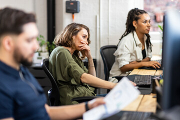 Stressed businesswoman sitting in front of desktop PC at office