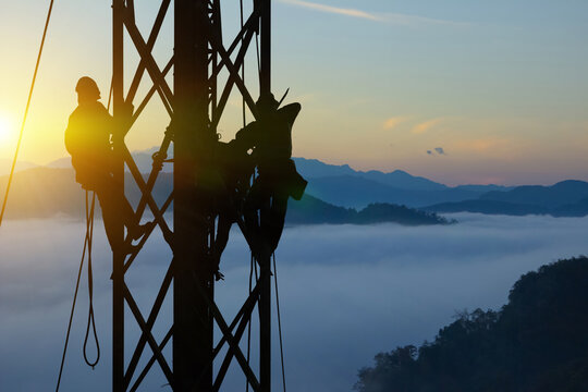 Silhouette workers on background of construction crews to work on high ground heavy industry and safety concept. Construction of the extension of high-voltage towers on beautiful nature background.