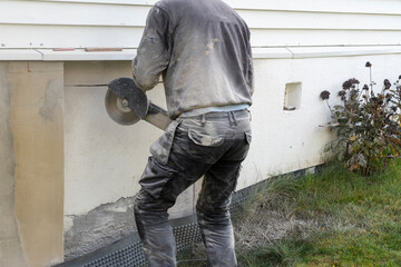 A man cutting beton wall of the house.
