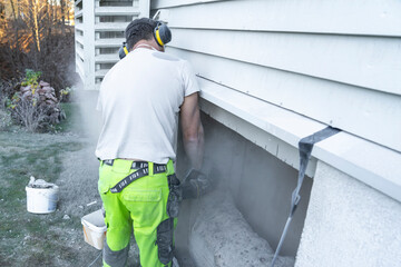 A man cutting beton wall of the house.
