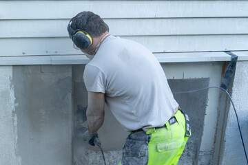 Cutting concrete wall with angle grinder and diamond disk.