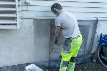 The builder using Angle grinder to cut the beton wall.