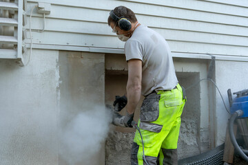 A man worker using a professional angle grinder to cut beton wall.