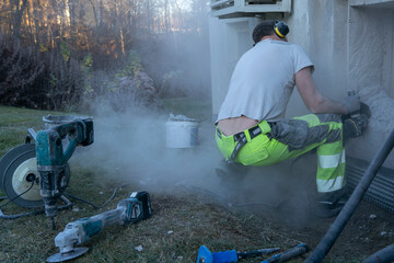 A man worker using a professional angle grinder to cut beton wall.