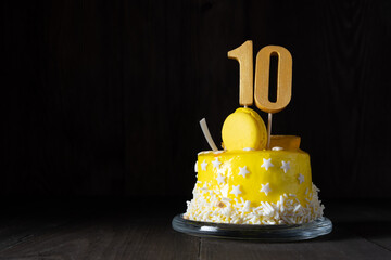 The number Ten on a yellow cake for an anniversary or birthday in a dark key