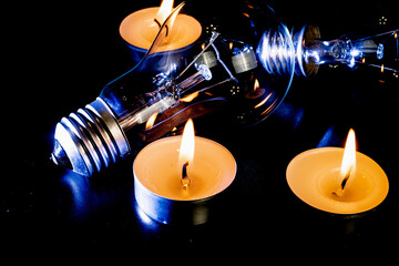 Electric lamp and candle on a dark background. Incandescent lamp and candle. No or power outage....