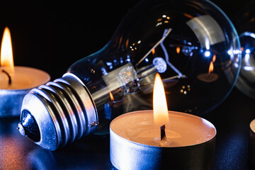 Electric lamp and candle on a dark background. Incandescent lamp and candle. No or power outage....