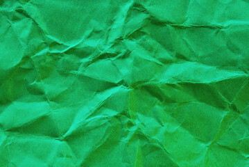 Green colored wrinkled paper texture, a sheet of recycled green paper as background 