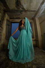 Naklejka premium beautiful girl in a blue evening dress in a ruined area