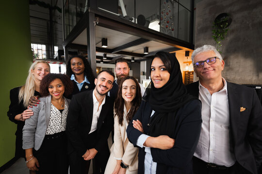 Portrait of large group of work with diverse ethnicity and age looking at camera smiling.