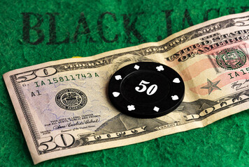 Black casino chip lies on a cash bill