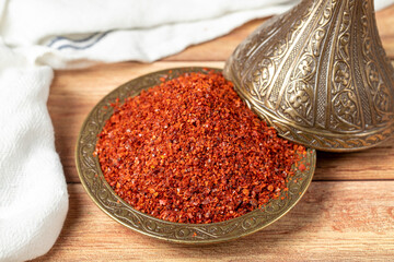 Red pepper flakes. Crushed chili pepper in bowl, dried chili flakes on wooden background. Close up