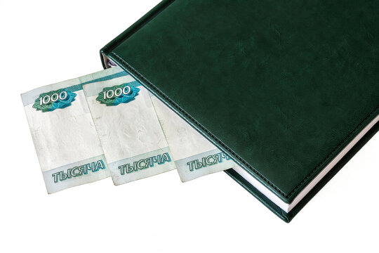 Against a light background lies a diary and part of Russian rubles