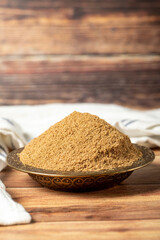 Powdered coriander spice. Coriander powder or dhaniya powder on wooden background. Dry spice concept. close up