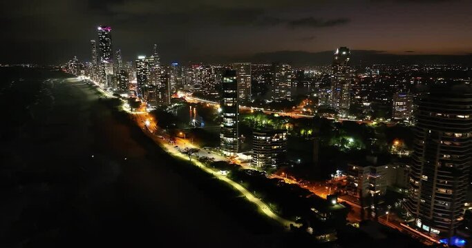 Breathtaking drone footage of the iconic Sufers Paradise cityscape at twilight featuring shimmering waves crashing on famous Gold Coast beaches