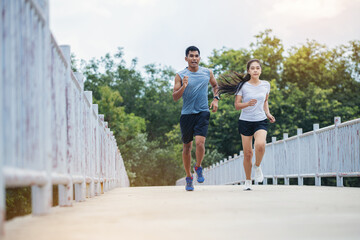 Young couple running together on road across the bridge. Couple, fit runners fitness runners during outdoor workout.