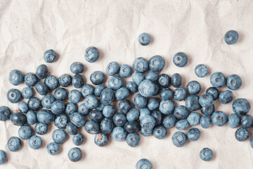 Fresh blueberries scattered on beige craft paper.