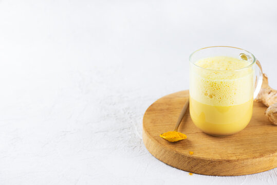 Indian golden milk from almond milk, ginger, turmeric and cinnamon in a cup, sugar and lactose free, copy space.