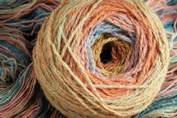 Ball of yarn from pure organic sheep's wool on an unwound skein of woolen threads. Rainbow color.