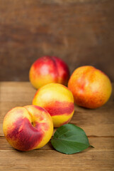 fresh nectarines with leaves on wooden background.