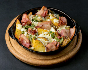potatoes with meat and cheese baked in the oven on a dark background