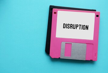 Pink vintage floppy disk on blue copy space background with text typed DISRUPTION, concept of radical transition change to industry due to technology innovation - obrazy, fototapety, plakaty