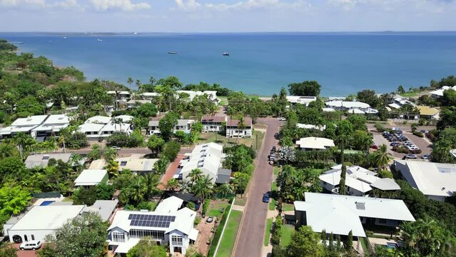 Aerial Drone over Luxurious Properties in residential neighbourhood suburb. Birds eye view of house roofs Tropical greenery palm trees. blue ocean sea. darwin city skyline