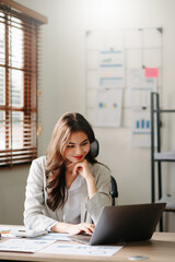 Young beautiful woman typing on tablet and laptop while sitting at the working wooden table  office