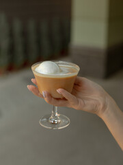 coffee is poured into a glass with ice cream for a glace coffee held by a woman arm