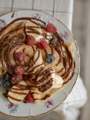 crepe dessert with banana, berries and chocolate on the table 