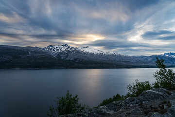 Norwegian fjord from a view point high above the fjord with snowcapped mountains and nice clouds in the night sky