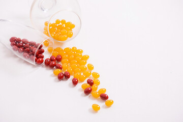 Tablets, capsules for vision. Red and yellow vitamins are poured onto the table from the glass. Diopter lenses, myopia, farsightedness. Healthy body, heart and bones. High quality photo