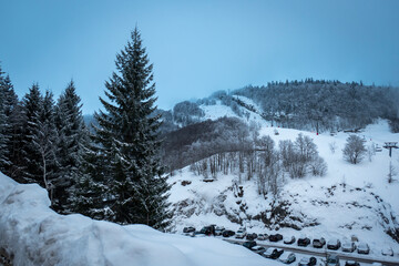Fototapeta na wymiar Montanhas cobertas de neve num dia frio de inverno com a instância de esqui ao fundo em Gourette nos Pirenéus Atlânticos, França