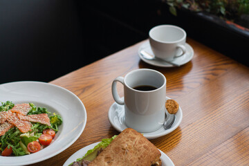 Full table of delicious and different dishes in cafe with cup of coffee in white dinnerware.