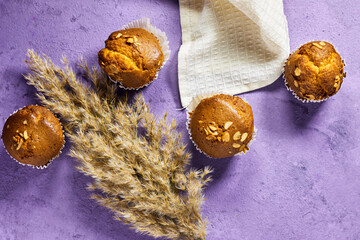 Vanilla Caramel Nuts Muffins In Paper Cups  with reeds plant On purple background