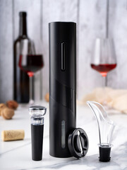 sommelier set: electric corkscrew, cork opener, aerator, vacuum stopper. In the background is a...