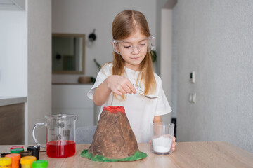 Little schoolgirl using soda to make chemical experiments at home. Little girl make easy scientific...