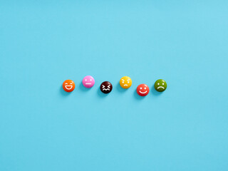 Joy, serenity, anger, happiness, sadness, delight, hate. Psychological mood swings. Variety of human emotions represented by emoticons on colored candies.