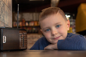 Adorable boy at the table in a cafe with a vintage old radio