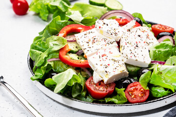 Greek salad with feta cheese, black olives, tomatoes, paprika, cucumber and red onion, healthy vegetarian mediterranean diet food. White background, top view