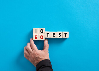 Male hand changes the word IQ test to EQ test on blue background. Choosing Emotional quotient over intelligence quotient.