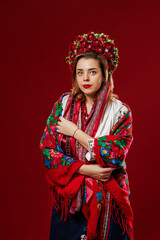 Portrait of ukrainian woman in traditional ethnic clothing and floral red wreath on viva magenta studio background. Ukrainian national embroidered dress call vyshyvanka. Pray for Ukraine