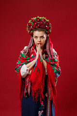 Portrait of ukrainian woman in traditional ethnic clothing and floral red wreath on viva magenta studio background. Ukrainian national embroidered dress call vyshyvanka. Pray for Ukraine