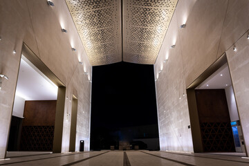 Illuminated courtyard of Mosque of Light in Dubai, facade and roof with triangular geometric patterns.