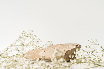 Beauty cosmetic product presentation made with stone and wild summer flowers.