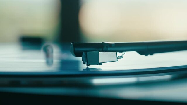 Side view of a record player needle sticking down from the cantilever. Turntable stylus on the vinyl disc. Retro music or modern dj station. 