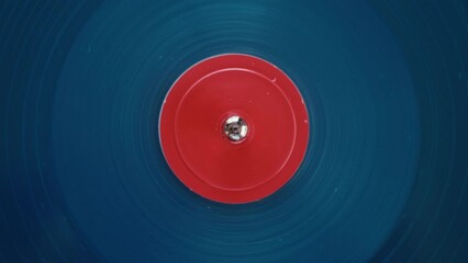 Top view of a blue vinyl record spinning around and playing music. New album release presentation or enjoying vintage music player at home. Hypnotic background. 