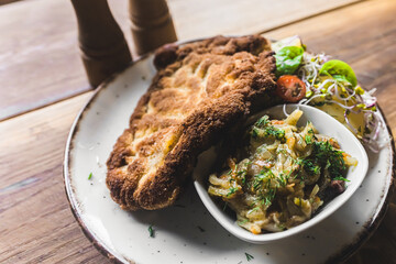 Top-down view of breaded fried pork cutlet schabowy with boiled potatoes and salad served on white plate. Polish cuisine. Horizontal indoor shot. High quality photo