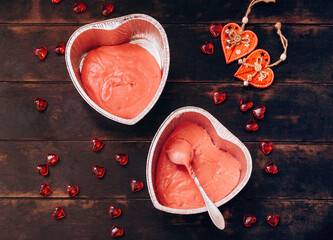 Fototapeta premium Two foil molds with red heart-shaped cake dough. Preparation for Valentine's Day