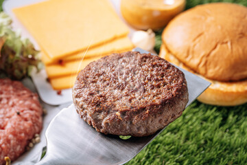 barbecue burger cutlet. barbeque concept in nature. barbecue spatula with a burger patty on it